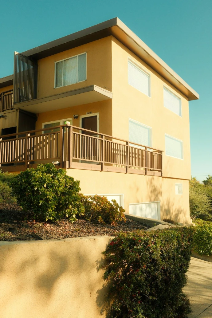 Modern yellow building with wooden balcony and glass details.