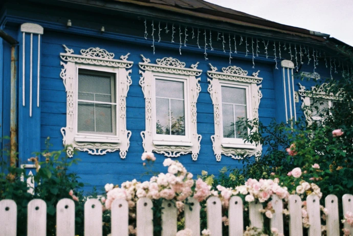 A house with blue paint exterior a white picket fence