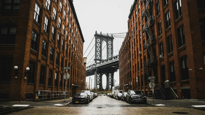 cars parked near brown building with Brooklyn Bridge in the background