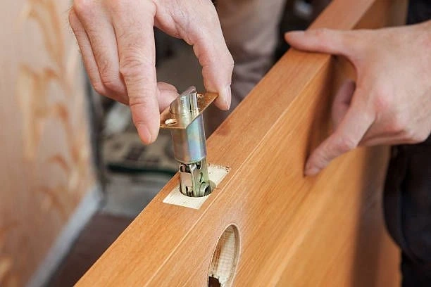 worker fitting door knob in a wooden door